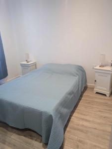 Néoulesにあるappartement dans le villageのベッドルーム1室(青いベッド1台、ナイトスタンド2台付)
