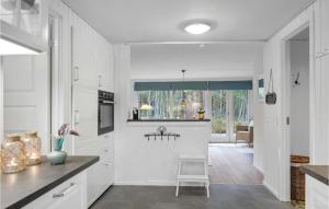 a kitchen with white cabinets and a chair in it at Holiday Home Gubbegårdsvejen Nexø Vi in Bedegård