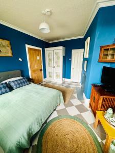 1 dormitorio con paredes azules, 1 cama y TV en Fitz House, en Keswick