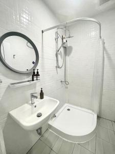 ein weißes Badezimmer mit Waschbecken und Spiegel in der Unterkunft PJ Hostel & Bar in Pattaya