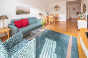 a living room with a blue couch and a glass table at Kleine Möwe 08 in Norderney