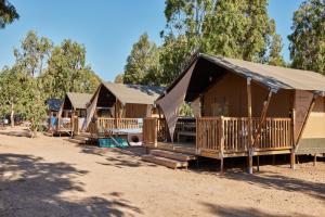 a row of wooden huts in a field at Glamping Costa Smeralda in Baraccamenti