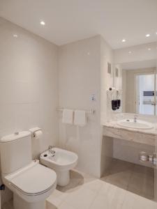 a white bathroom with a toilet and a sink at Apartamentos La Santa Maria in Cala Millor