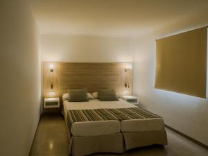 a bedroom with a bed and two lights on the wall at Apartamentos La Santa Maria in Cala Millor +12 photos