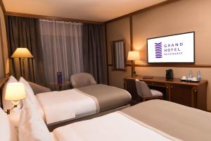 a hotel room with two beds and a flat screen tv at Grand Hotel Bucharest in Bucharest