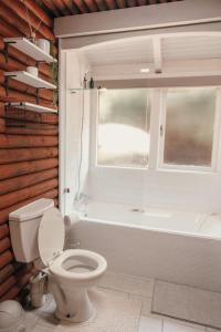 a bathroom with a toilet and a tub and a window at Riverside Self Catering Cabin in Wilderness