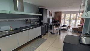 a kitchen with white cabinets and a living room at Charming Lake House nature retreat in Cotswold Water Park, South Cerney near Cirencester in Cirencester