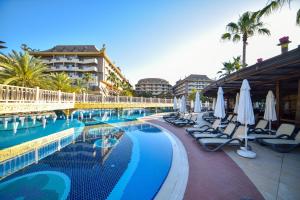a resort swimming pool with lounge chairs and umbrellas at Royal Dragon Hotel in Side