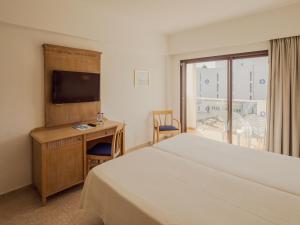 ein Schlafzimmer mit einem Bett, einem Schreibtisch und einem Fernseher in der Unterkunft Hotel Santa Maria Playa in Cala Millor