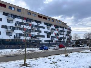 ein großes Wohnhaus mit im Schnee geparkten Autos in der Unterkunft Apartman Komenského-Centrum in Banská Bystrica