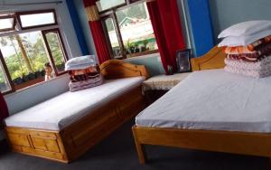 two beds in a room with two windows at Simma Homestay By StayApart in Pedong +15 photos