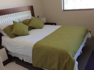 Reñaca Park Apartment في فينيا ديل مار: غرفة نوم بسرير كبير ومخدات خضراء