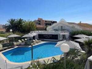 a swimming pool with umbrellas and chairs and a hotel at Hôtel Eve Cap d'agde Village Naturiste in Cap d'Agde