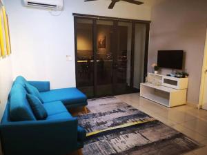 a living room with a blue couch and a television at WOODSBURY PREMIER LUXURY SUITE 2B2R 2MIN SUNWAY in Butterworth