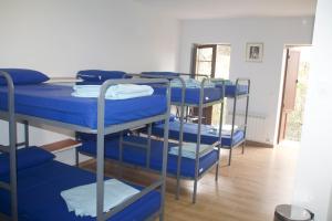 grupa niebieskich łóżek piętrowych w pokoju w obiekcie Albergue Parroquial Santiago Apostol de Redondela w mieście Redondela
