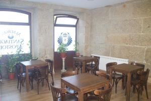 restauracja z drewnianymi stołami i krzesłami w pokoju w obiekcie Albergue Parroquial Santiago Apostol de Redondela w mieście Redondela