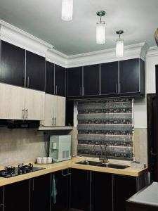 a kitchen with black cabinets and a sink and a microwave at D23 Homestay Bandar Baru Bangi, Selangor in Bandar Baru Bangi