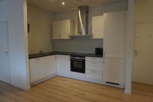 a kitchen with white cabinets and black counter tops at Zen Beach Apartment in Noordwijk aan Zee
