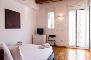 une chambre blanche avec un lit et une télévision dans l'établissement Moderno y auténtico en el corazón de Poble Sec, à Barcelone