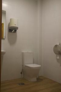 łazienka z toaletą i dozownikiem papieru na ścianie w obiekcie Albergue Parroquial Santiago Apostol de Redondela w mieście Redondela