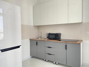 a kitchen with white cabinets and a microwave on a counter at Квартира в центре Астаны in Astana