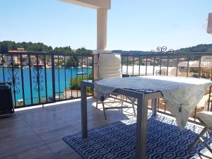 a table and chairs on a balcony with a view of the water at Hamo Apartments & Soba in Lumbarda