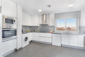 a white kitchen with white cabinets and a window at The Corner Apartments by Aspasios in Barcelona +42 photos