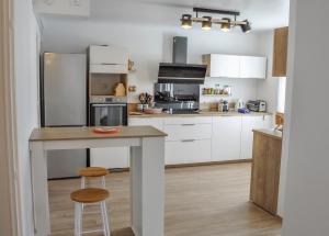 a kitchen with white cabinets and a table with a stool at T2 indépendant Villa Héas in Argelès-Gazost