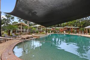 una piscina en un complejo con sillas y edificios en Seven Mile Beach Holiday Park en Gerroa