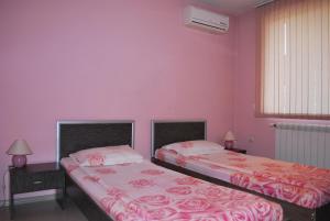 two beds in a room with pink walls at Hotel Milenium in Sofia