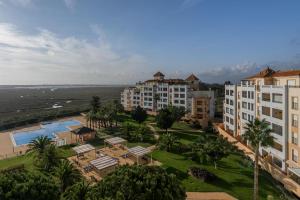 une vue aérienne d'un complexe hôtelier et de l'océan dans l'établissement Las Marismas Atico PLUS by Ĥ - Isla Canela Golf GLHM59P19, à Isla Canela