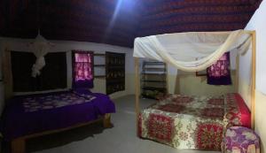 a bedroom with a bed and a canopy at Campement Courbine in Ndangane