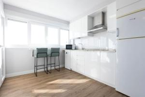 a white kitchen with white cabinets and bar stools at Goizalde - Basquenjoy in Fuenterrabía +31 photos