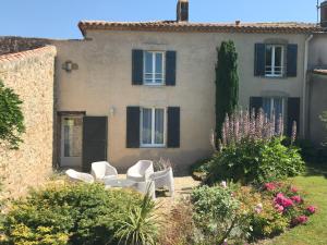 un patio con sillas blancas frente a una casa en Chambres d'Hôtes Les laitières, en Beaurepaire