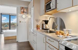 a kitchen with white cabinets and a sink and a bed at Fanø Bad, Lejl 53 in Fanø