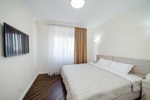 a white bedroom with a bed and a window at Elegant stay near the Park in Chişinău