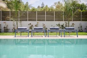 three benches sitting next to a swimming pool at River Serenity Villa Vryses - Private Pool in Vryses