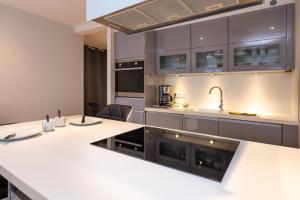 a kitchen with white counter tops and gray cabinets at Le Doumer parking wifi in Vannes