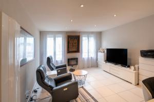 a living room with two chairs and a flat screen tv at Le Doumer parking wifi in Vannes