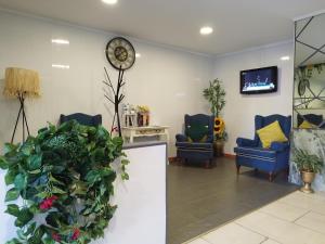 a waiting room with two chairs and a clock on the wall at Alojamento Central I - Funchal in Funchal