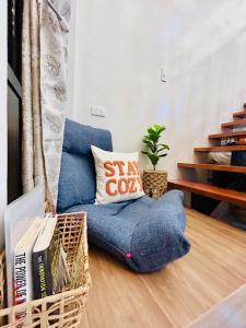 a living room with a blue chair with a pillow at Tagaytay's Cozy Loft-type Forest House and Camp in Silang
