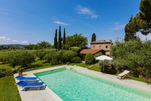 a swimming pool with two chairs and a house at Villa Scianellone in Torrita di Siena