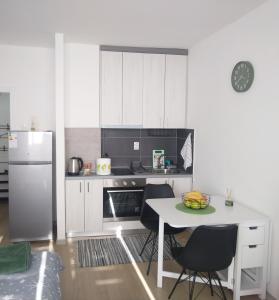 una cucina bianca con tavolo e frigorifero di Una Studio Apartman a Sombor