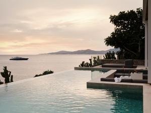 a swimming pool with a cruise ship in the water at Bill&Coo Mykonos-The Leading Hotels of the World in Mikonos