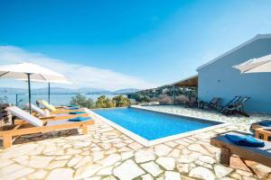 a villa with a swimming pool with chairs and umbrellas at Villa Katostrato Beach by Villa Plus in Apraos