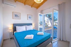 a bedroom with a blue bed and a balcony at Villa Katostrato Beach by Villa Plus in Apraos +13 photos