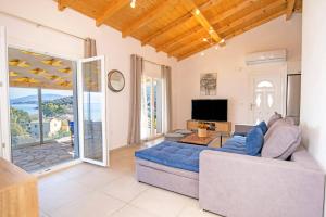a living room with a couch and a tv at Villa Katostrato Beach by Villa Plus in Apraos