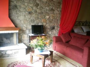 a living room with a red couch and a stone wall at Ktima Kletsa in Graviá