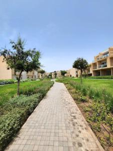a brick path in a park with trees and buildings at Luxueux appartement de plage Surf & Golf Néroli 13 in Tamraght Ouzdar