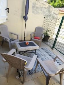 a patio with chairs and tables and an umbrella at Maison prés d'Agen in Bon-Encontre